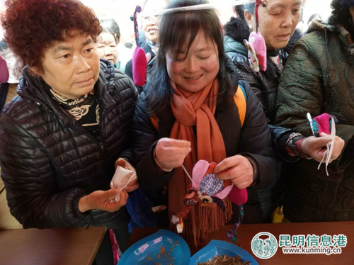活动现场，龙院社区党支部成员在现场手把手都社区居民缝制手工香包