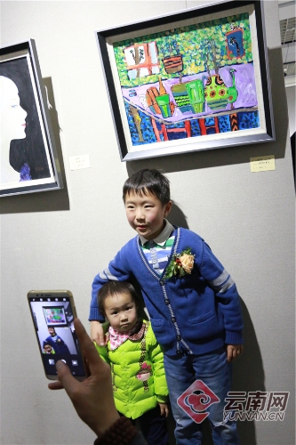 “小画家”和自己的作品合影留念。